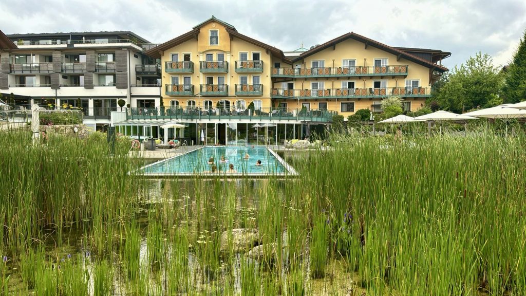 Blick von den Liegeflächen im Außenbereich auf Das Stemp, den Infinity Pool und den Naturbadeteich