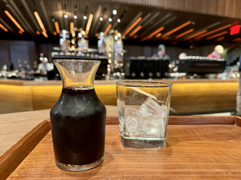 Whiskey Glas gefüllt mit Eis und Karaffe mit Whiskey Barrel Aged Cold Brew in der Starbucks Reserve Roastery in New York