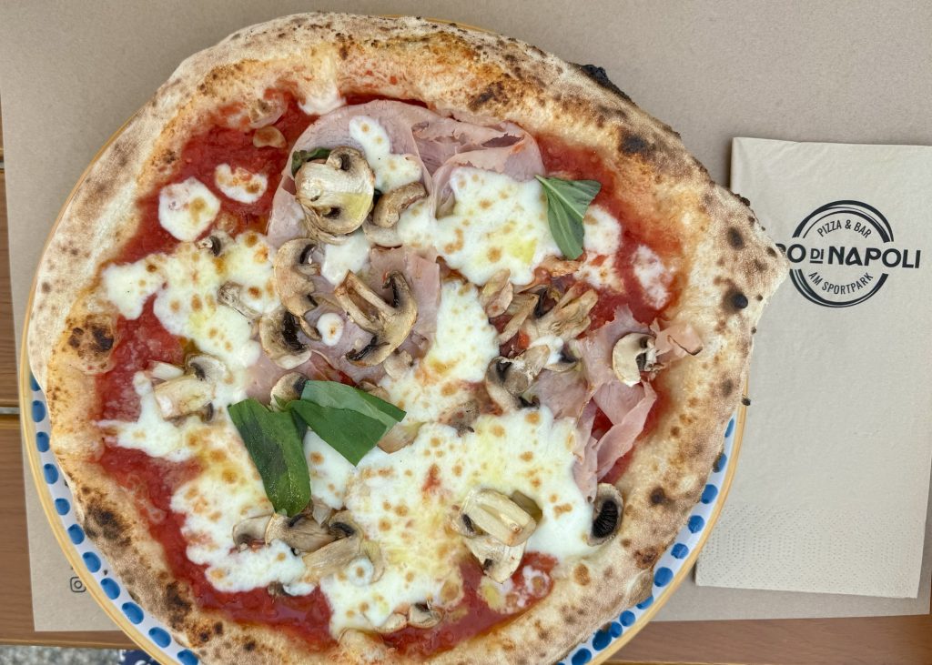 Pizza belegt mit Tomatensauce, Fior di Latte, Schinken und Pilzen im Oro di Napoli in Hallbergmoos